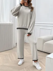 Close-up view of a beige two-piece knitted lounge set featuring elegant black striped trim