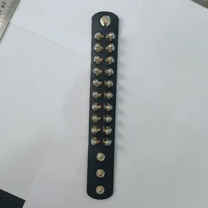 Top view detail of black leather punk wristband featuring double rows of conical metal studs