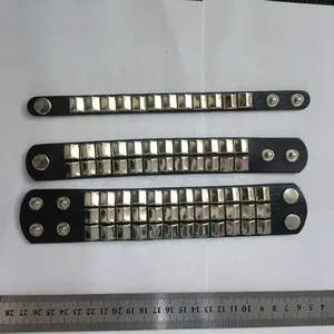 Detailed top-down view of three punk leather bracelets with silver square studs and metal ruler.