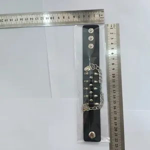 Détail d'un bracelet en cuir punk avec rivets et chaîne indiquant les mesures