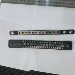 Detailed view of the hardware on two black punk leather bracelets with studs and stars
