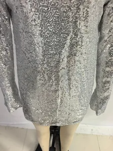 Macro detail of shimmering silver sequins on a stylish long-sleeved mini party dress