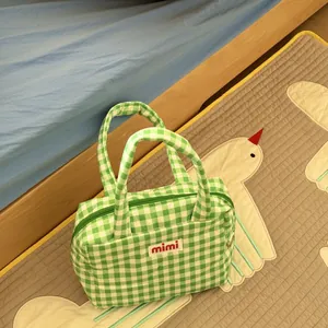 Close-up view of a cute green and white checkered tote bag with mimi label in home room