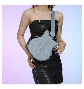 Close-up of a blue guitar-shaped crossbody bag with rivet details worn by a model