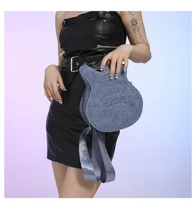 Close-up of guitar-shaped blue denim bag held by model wearing a black leather mini dress