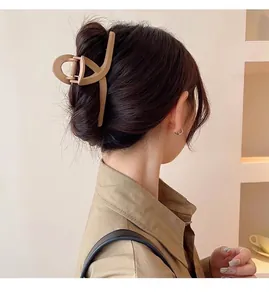 Macro detail of a large matte khaki hair claw clip securing a sophisticated bun
