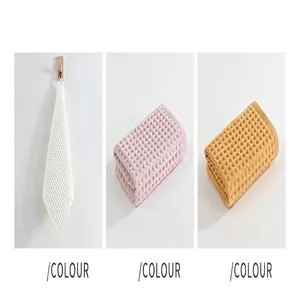 Detail view of waffle cotton face towels in beige, pink, and yellow colors.
