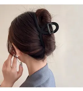Macro detail of matte black large hair claw clip securing a thick hair bun hairstyle