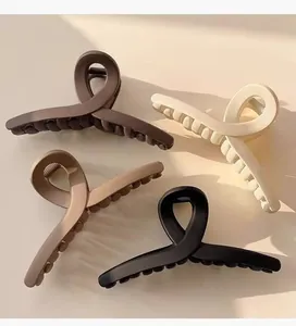 Close-up view of four large matte hair claw clips in various neutral earth tones