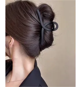 Detailed view of a matte black large hair claw clip holding thick hair in a stylish bun
