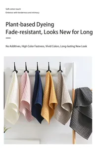 Multiple colorful waffle weave cotton hand towels hanging on hooks in a bathroom