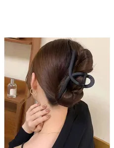 Detailed close-up view of a large matte black hair claw clip styled in a classic updo