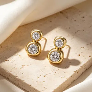 Elegante goldene Ohrstecker mit zwei runden Zirkonia auf einem feinen Steinuntergrund