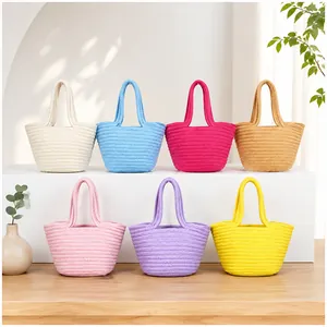 Collection of handmade woven cotton rope hand-bags in various colors on a white display.