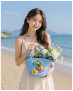 An elegant Asian model holding a light blue hand-woven flower basket bag on a beach