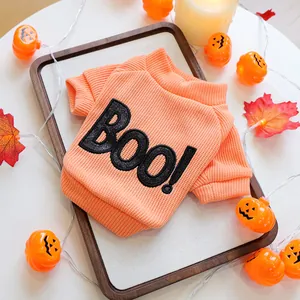 Detail view of an orange knitted Halloween dog sweater with sparkling 'BOO!' embroidery