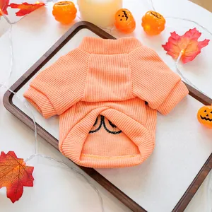 Close-up of orange knitted pet sweater with festive Halloween pumpkin design
