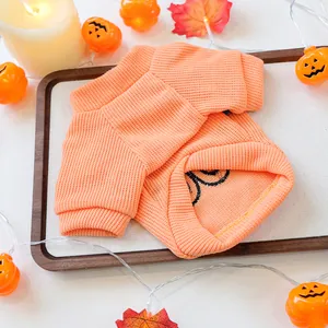 Detailed macro view of a soft orange knitted Halloween pet sweater with festive decor