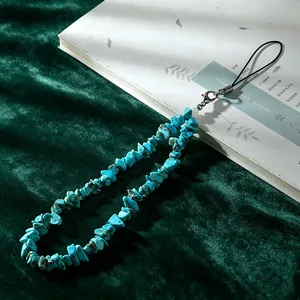 Macro view of a natural turquoise chip stone phone lanyard strap on green velvet