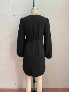 Detailed back view of a black long-sleeved dress with textured dots and waist belt