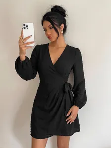 Close-up of elegant black V-neck Swiss dot dress with long sleeves and adjustable waist tie
