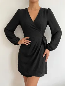 Detailed view of an elegant black Swiss dot V-neck long-sleeved wrap dress design.