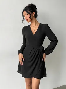 Detailed view of an elegant black long-sleeved V-neck Swiss dot wrap mini dress on a model