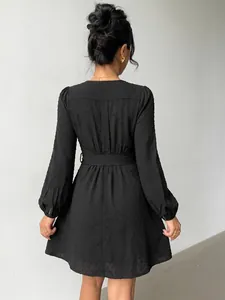 Elegant back view of black Swiss dot long sleeve mini dress featuring a belted waistline