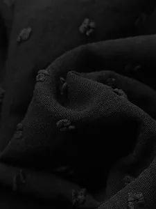 Close-up macro view showing the textured black clip dot fabric of an elegant dress