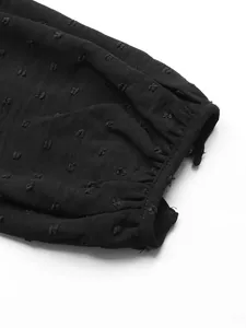 Detailed macro view showing the textured black Swiss dot fabric on a long sleeve cuff