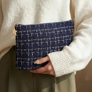 Elegant navy tweed cosmetic bag with gold star zipper pull, portable handheld clutch