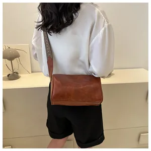 Rear view of a minimalist brown pillow bag featuring a stylish wide crossbody strap