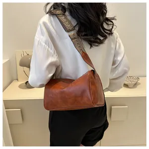Vintage brown faux leather pillow bag with wide patterned strap shown on a model's back