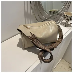 Chic beige pillow handbag featuring a wide ethnic patterned shoulder strap on white surface