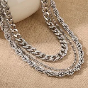 Détail rapproché de colliers multicouches en acier inoxydable argenté sur tissu beige.