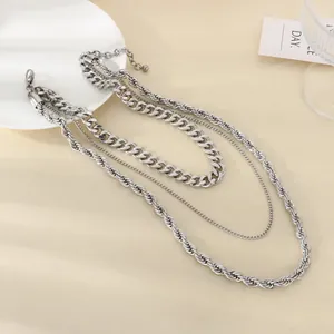 Détail d'un collier multicouche en acier inoxydable argenté, chaîne cubaine et style corde