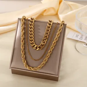 Détail de colliers multicouches dorés (chaîne cubaine et corde) sur un présentoir à bijoux.