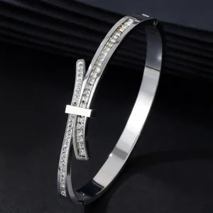 Close-up of silver stainless steel bangle with pavé-set square crystals and bow design