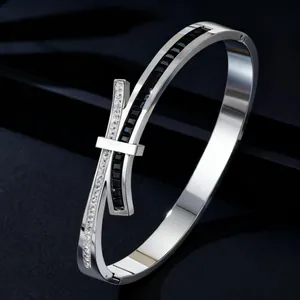 Detail view of a stainless steel bow-shaped bangle featuring black and white zircon stones