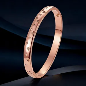 Detail view of a rose gold stainless steel bangle with elegant star engravings and crystals.