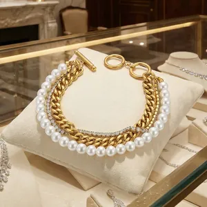 Detailed view of layered gold chain bracelet with shell pearls, zircons, and OT buckle.