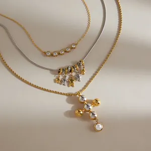 Nahaufnahme von mehrlagigen Edelstahlketten mit goldenen Sternen und Kreuzanhänger