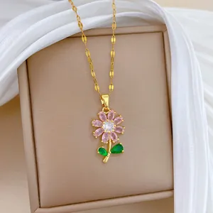 Gros plan d'un collier en acier titane doré avec un pendentif fleur en zircon rose brillant