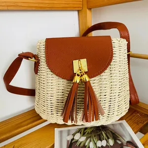Vue détaillée du sac en paille tressée avec rabat en cuir marron et glands décoratifs