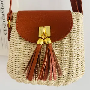 Détail d'un sac en paille tissé à la main avec rabat et glands en cuir marron.