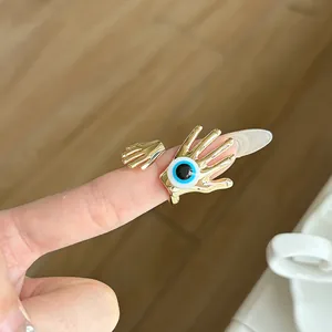 Macro view of a vintage gold hand-shaped ring featuring a blue evil eye detail.