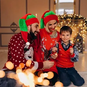 Happy family wearing long red and green striped plush Christmas hats in a warm festive setting