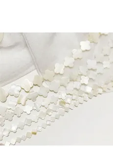 Close-up macro detail of natural white shell four-leaf clover beads for jewelry making