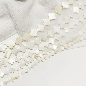 Close-up of polished natural white shell four-leaf flower beads for DIY jewelry