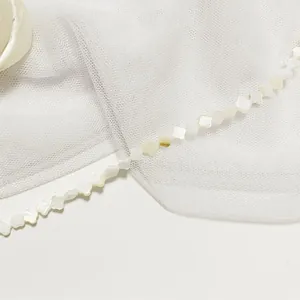 Macro view of natural white shell four-leaf clover shaped beads for DIY jewelry making
